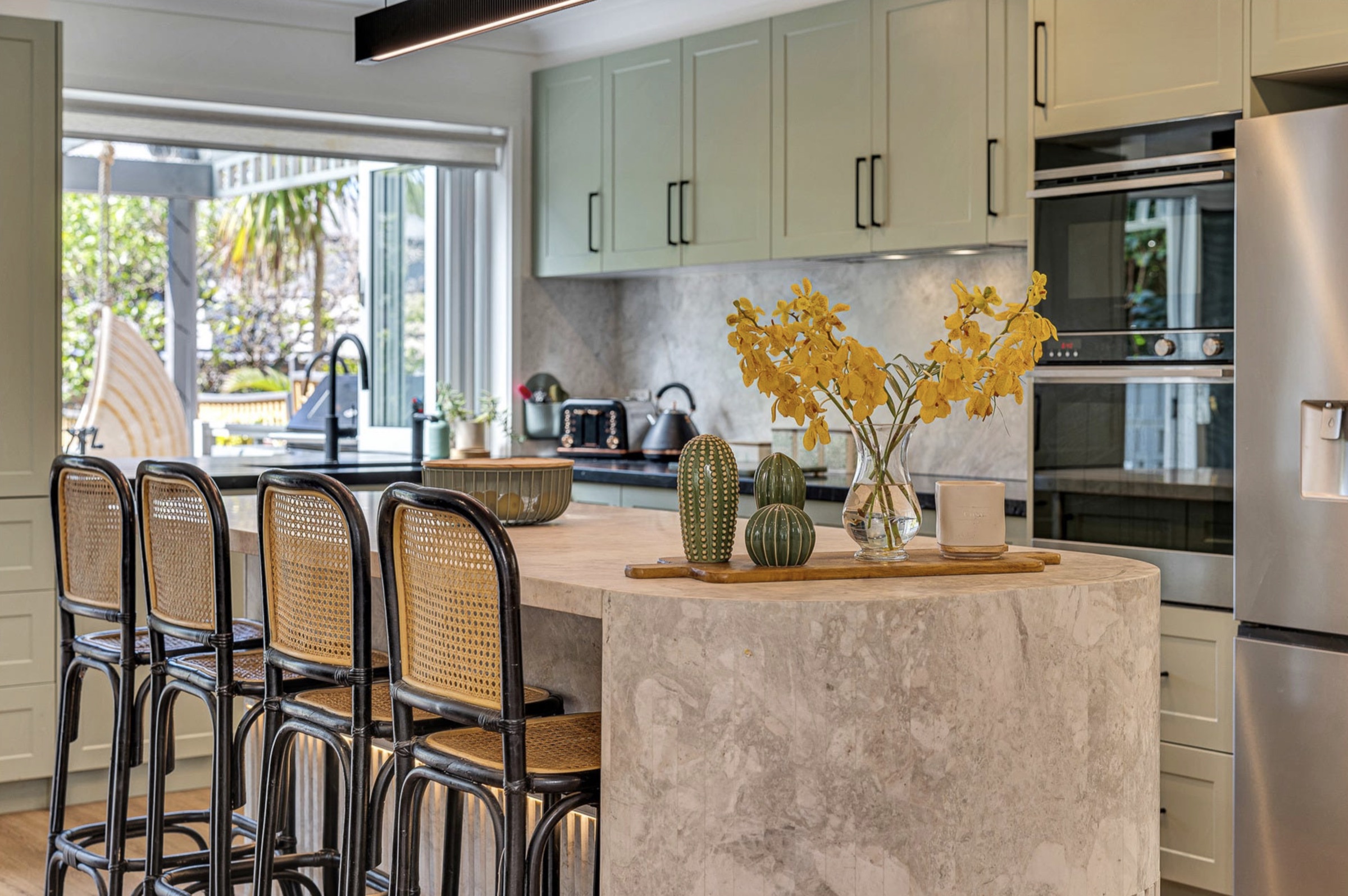 Curved waterfall edge of the dolomite island with rattan bar stools