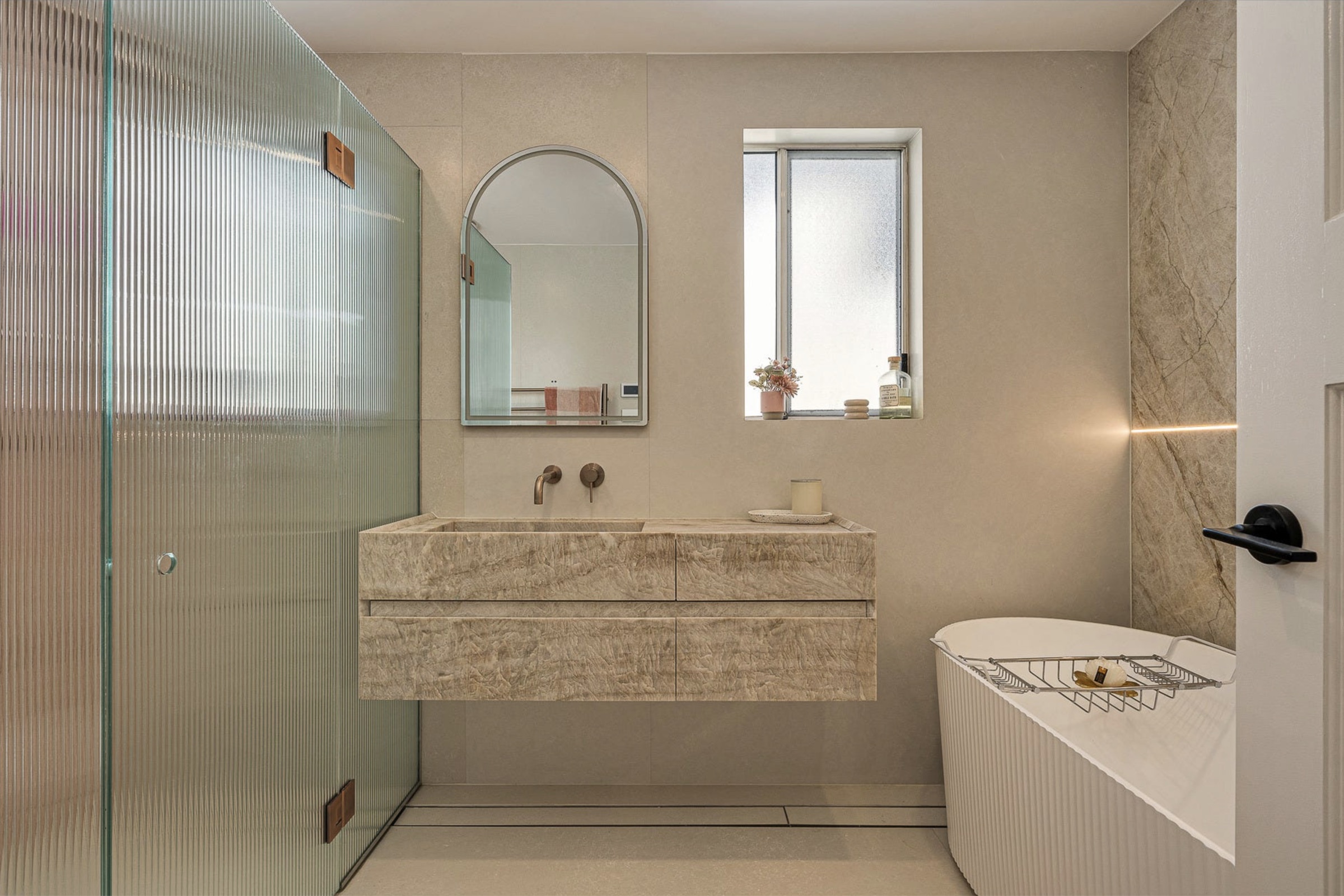Ensuite with natural stone floating vanity, arched mirror and freestanding bath